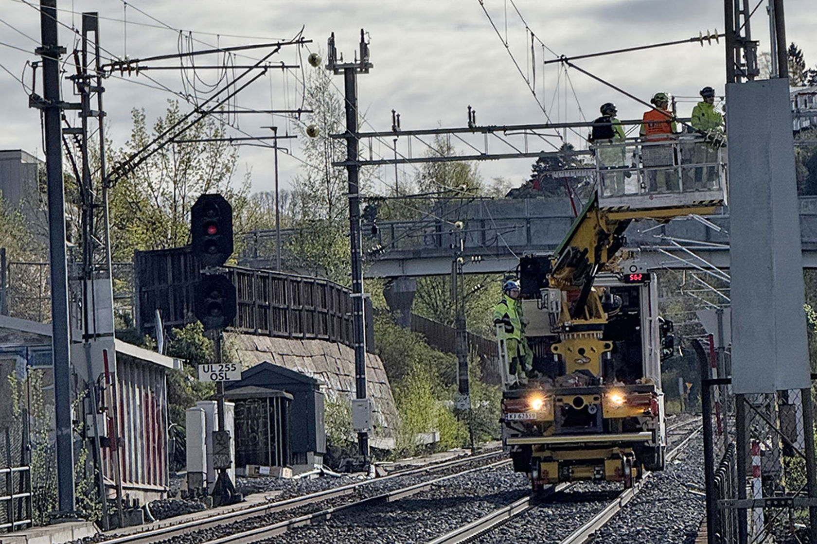 Arbeidsmaskin på sporet, tre personer i en lift jobber med kontaktledningen.