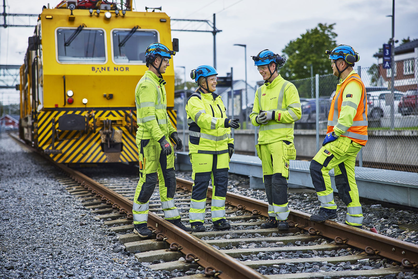 Fire kolleger står i sporet og snakker foran arbeidstog